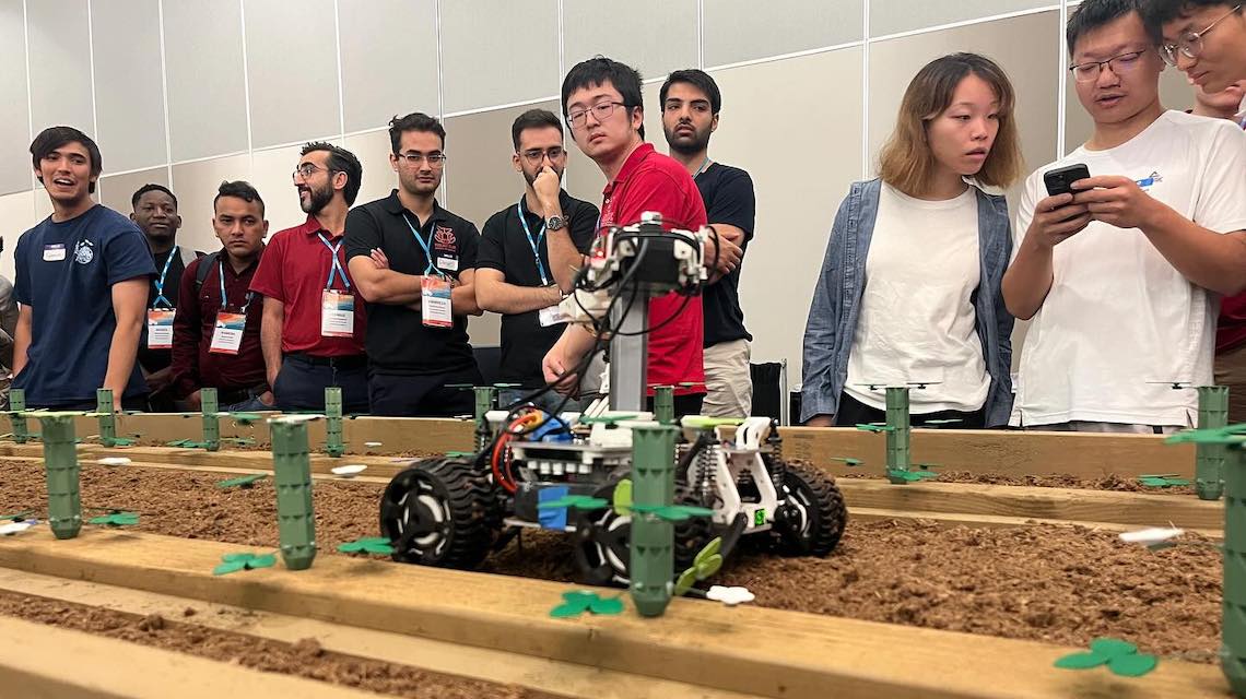 student watch robot trim strawberry plants